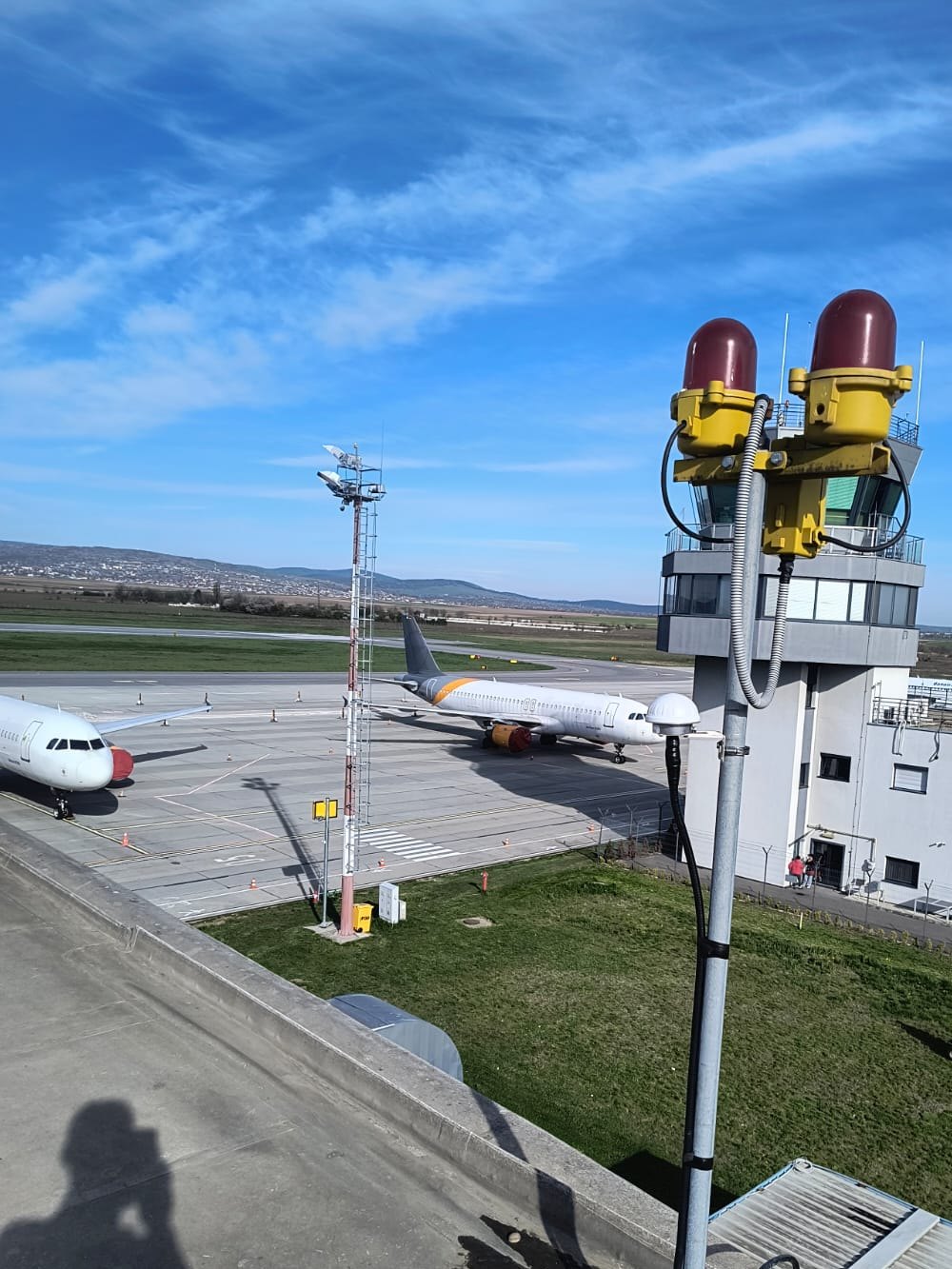 Antena de sincronizare GPS pe acoperișul terminalului, cu turnul de control și pista în fundal