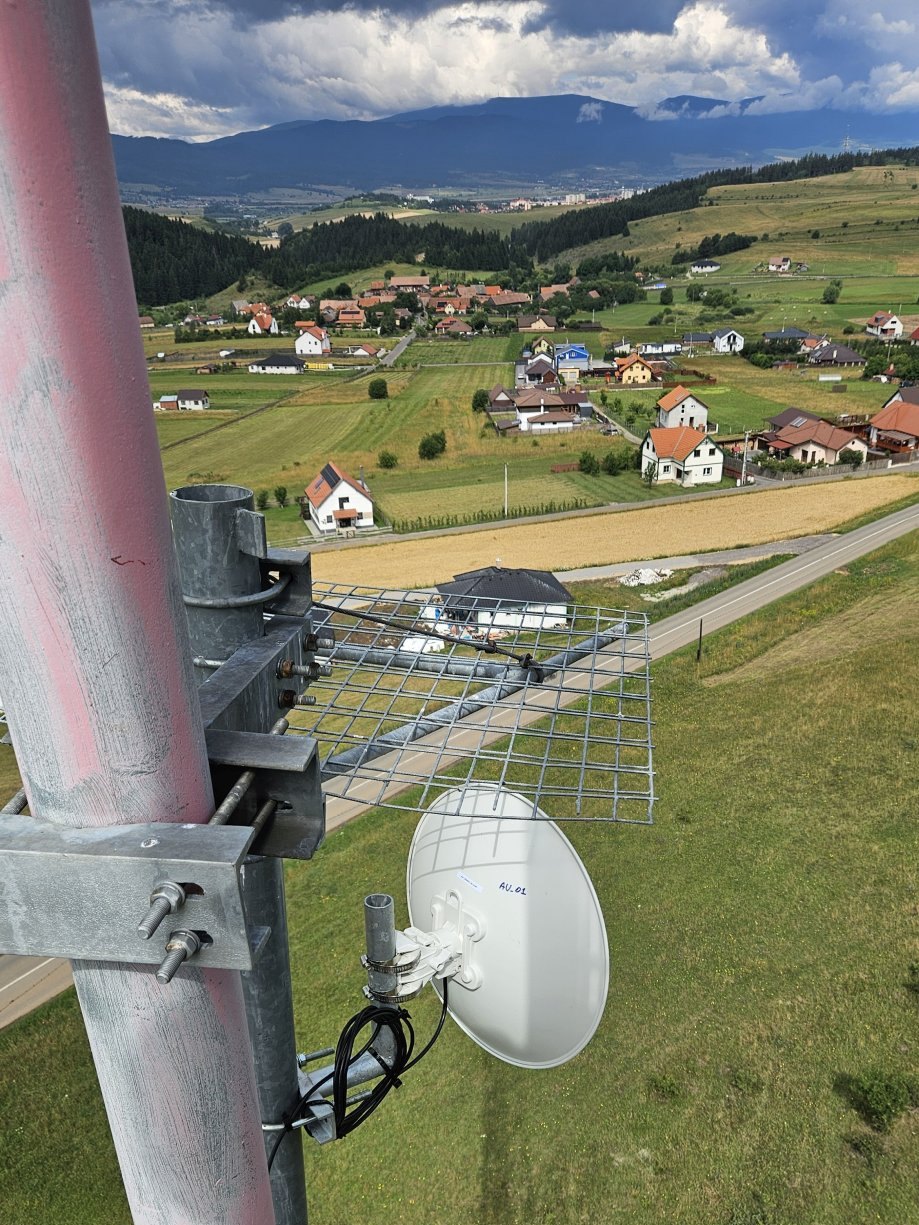 Antenă de radioreleu montată pe pilon, deasupra unei localități din vale