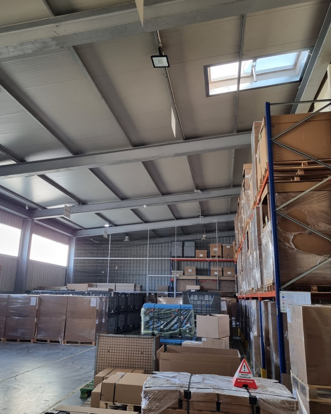 Interior de hală industrială cu structură metalică, cu paleți și cutii pregătite pentru expediție