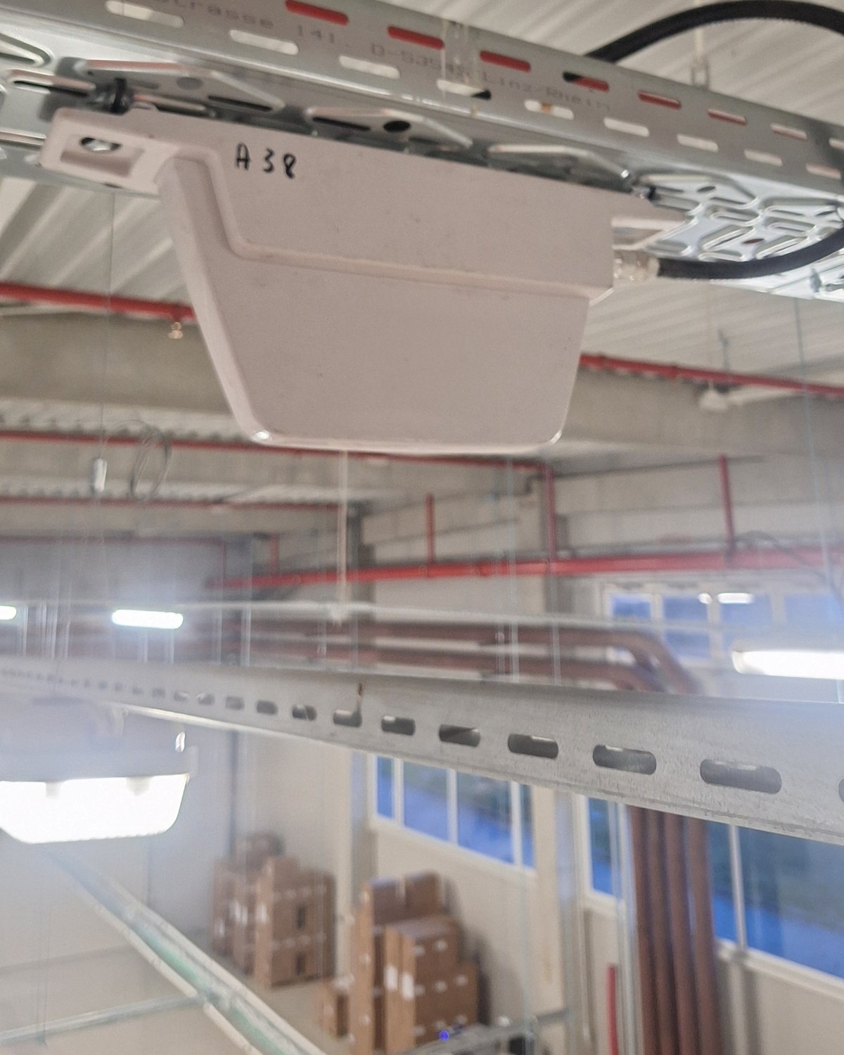 Antenă panou montată pe patul de cabluri, sub tavanul unei hale industriale