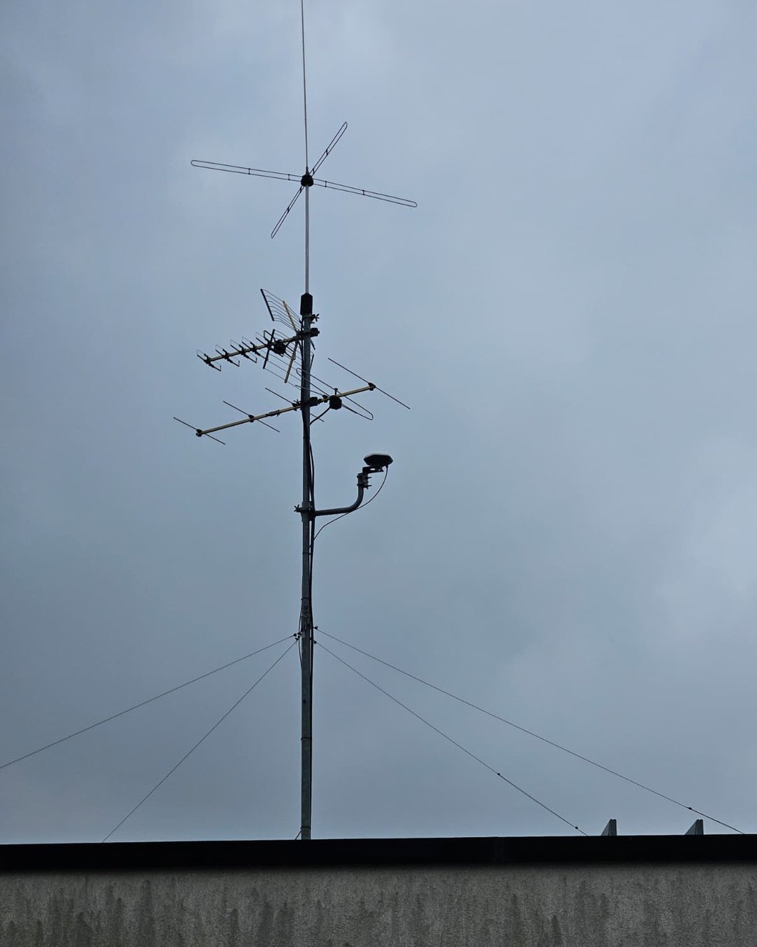 Pilon pe acoperiș cu antena donor GPS montată pe un braț, pe fundalul cerului