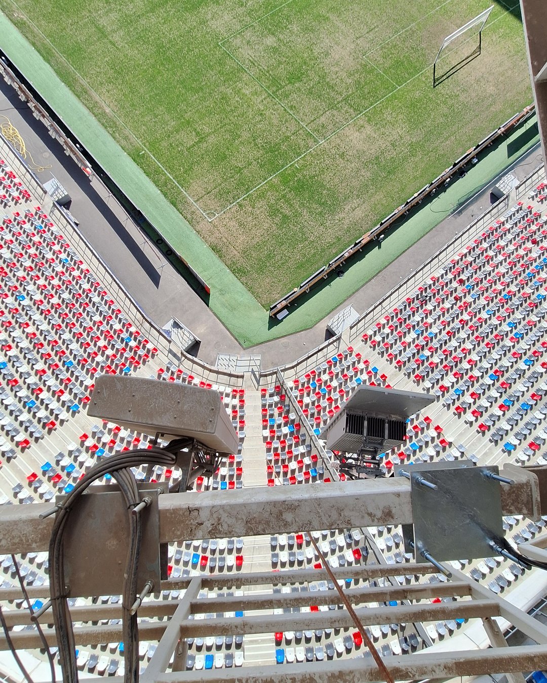 Vedere de sus de pe pasarela acoperișului: antena multibeam orientată spre tribune și antena activă 5G, cu gazonul și scaunele stadionului mult mai jos