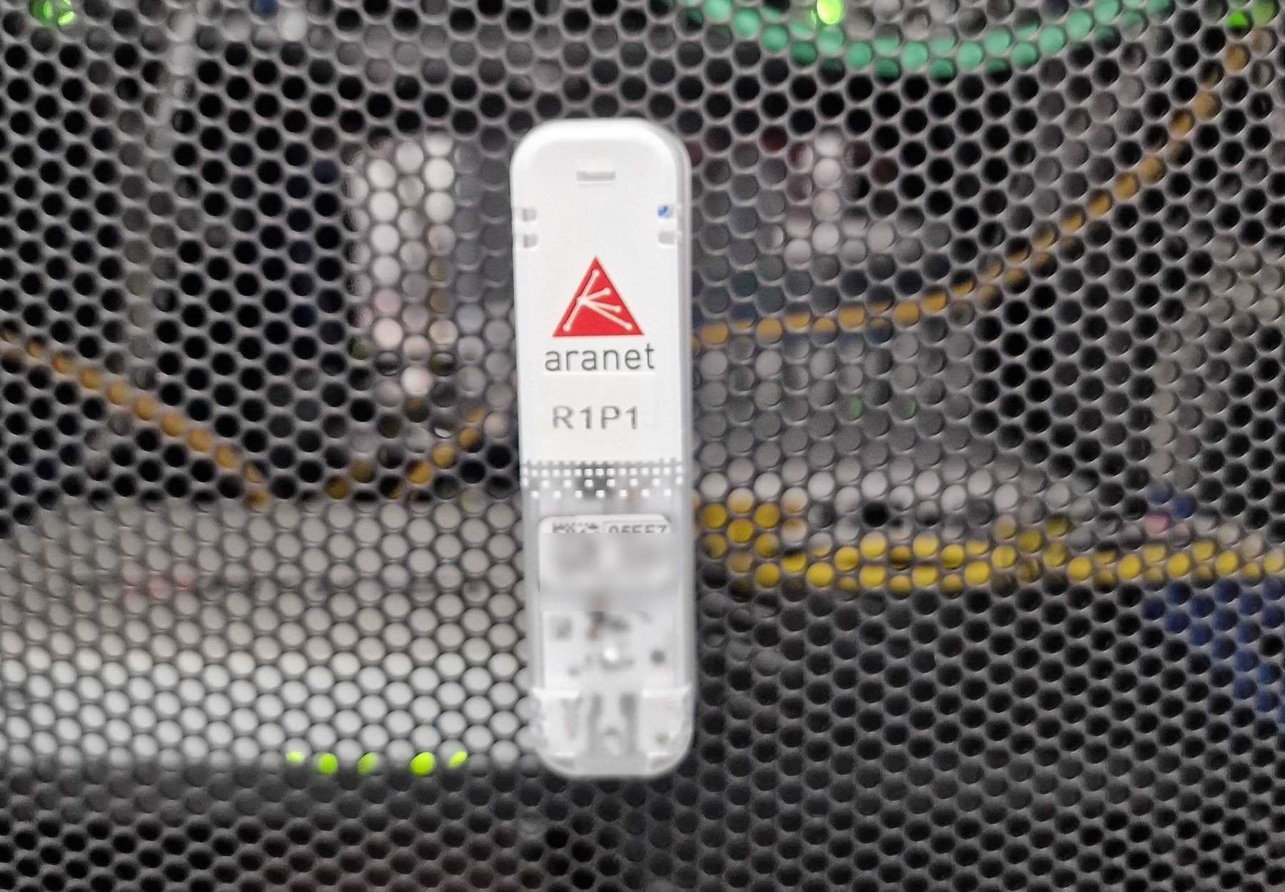 Senzor wireless Aranet montat pe ușa perforată a unui rack de centru de date