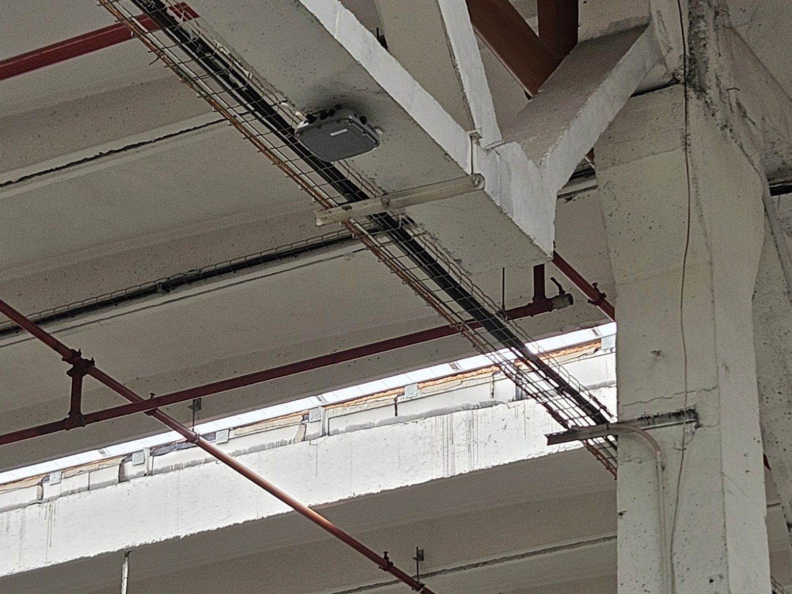 Access point industrial montat pe grinda unei hale, lângă traseul de cablare pe pat de sârmă