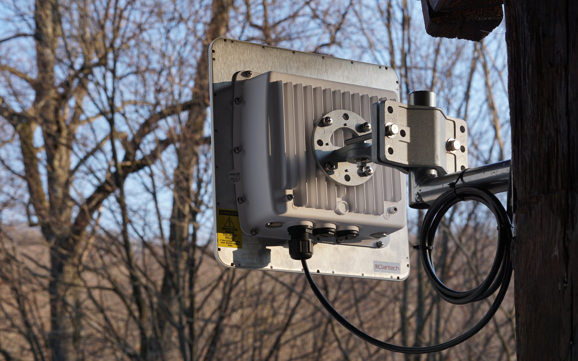 Antena legăturii radio punct la punct, montată pe structura de lemn a cabanei, cu pădurea în fundal