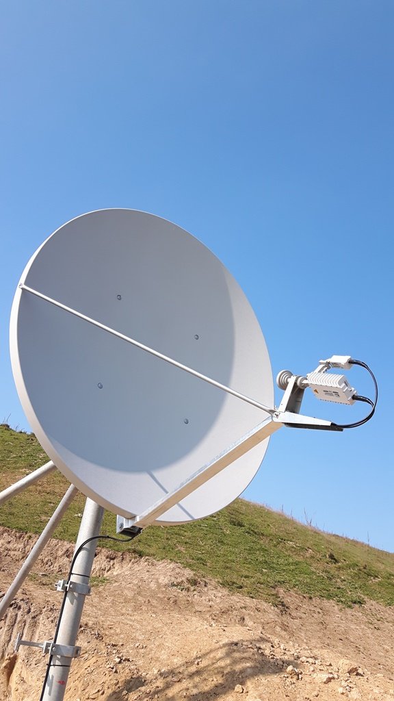 Antenă VSAT proaspăt instalată pe un site de deal, pe cer senin