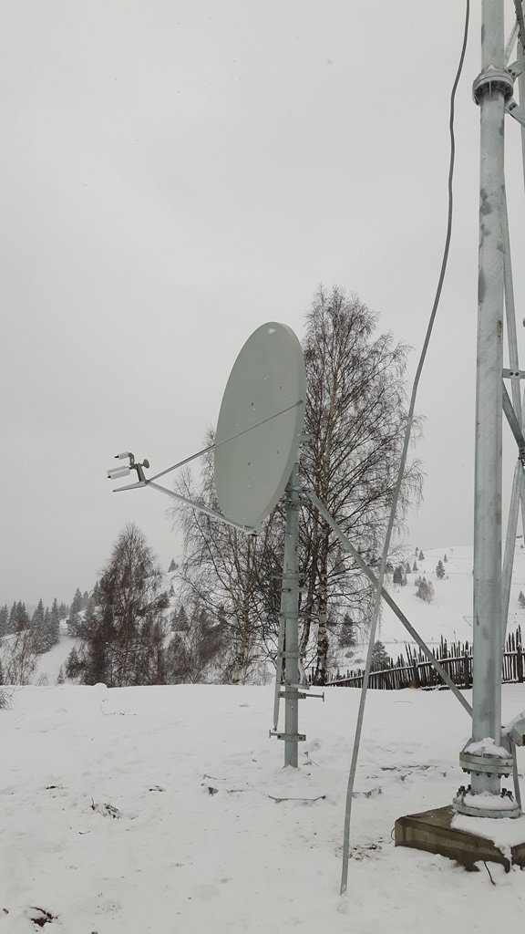 Antenă VSAT instalată iarna, într-un peisaj montan înzăpezit