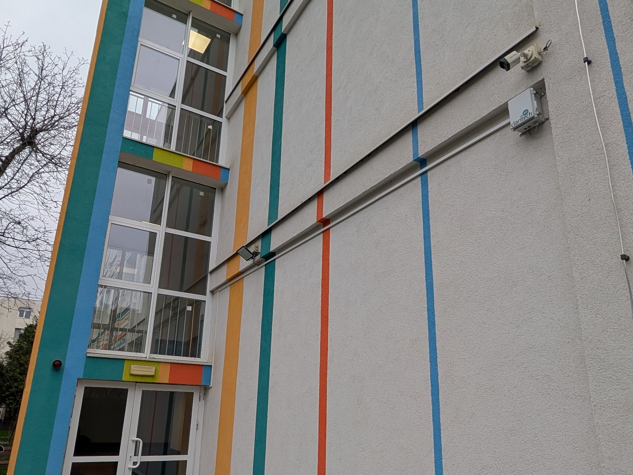 Stație de monitorizare a calității aerului montată pe fațada colorată a unei școli