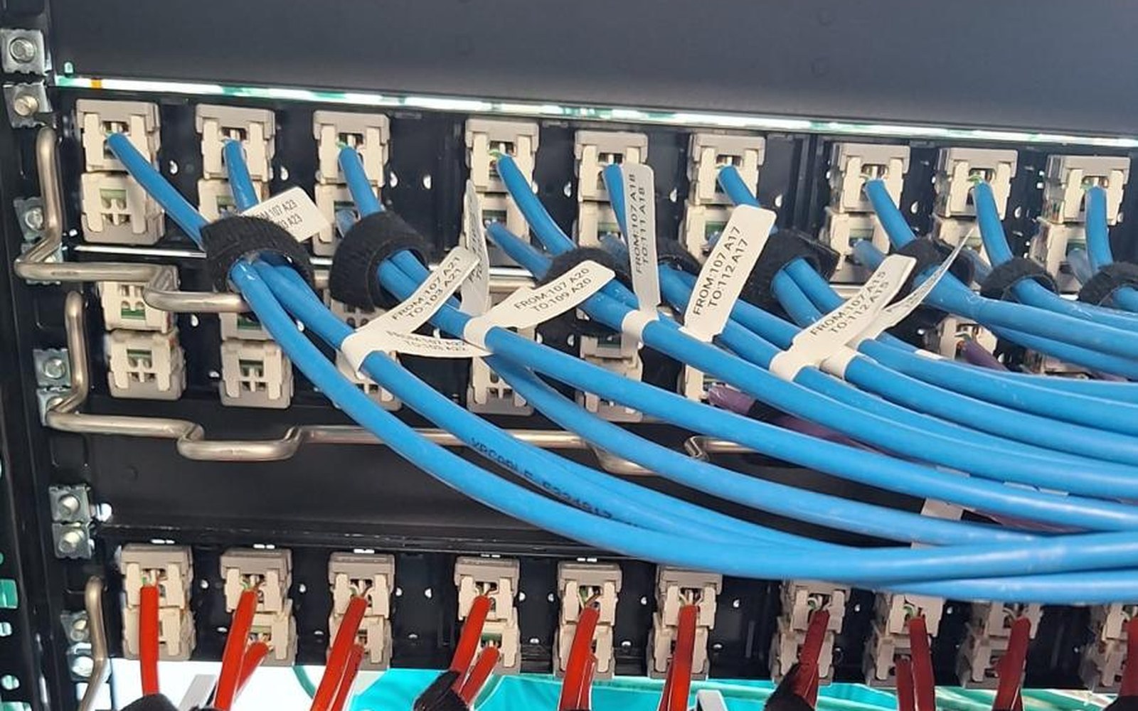 Patch field with labeled blue and red patch cords connected to the panels in the distribution rack