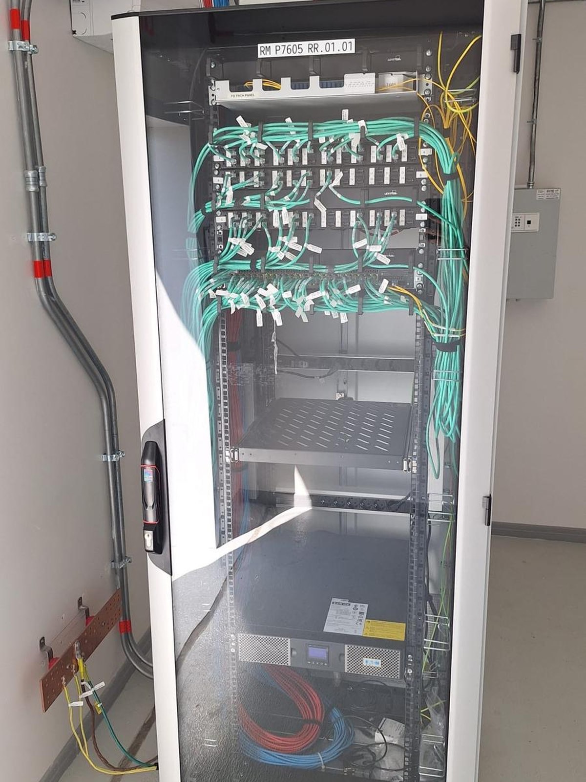 Glass-door rack in a finished technical space, with patch panels