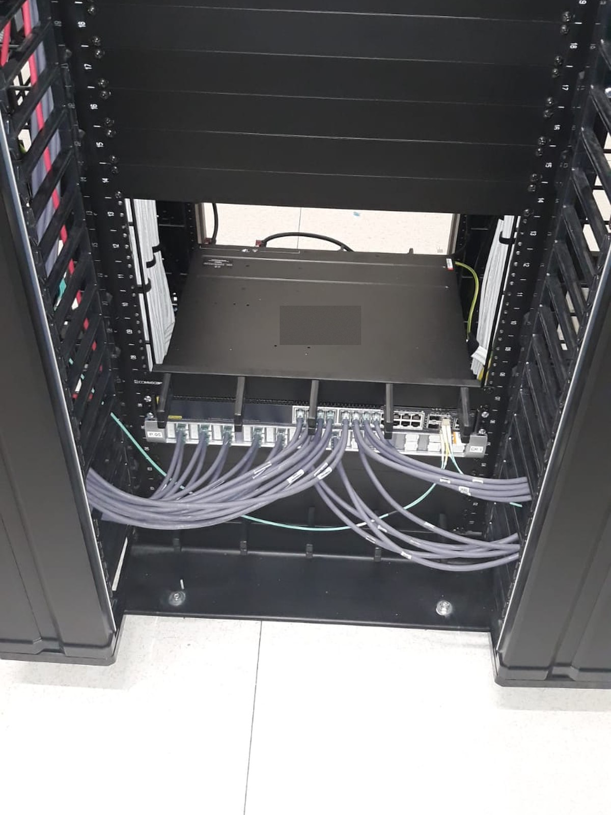 Rack de servere cu organizatoare verticale și patchcord-uri conectate la switch